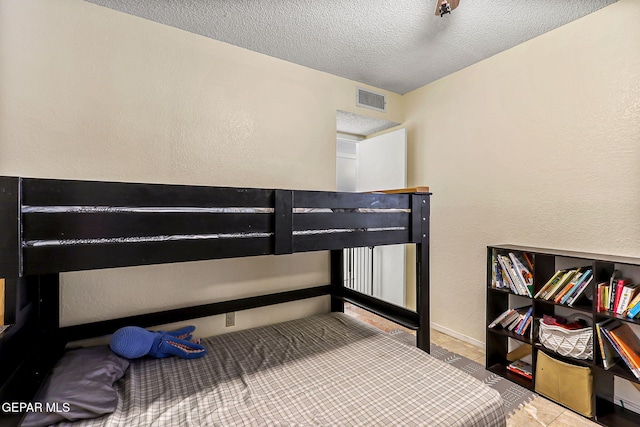 bedroom with visible vents, a textured ceiling, and a textured wall