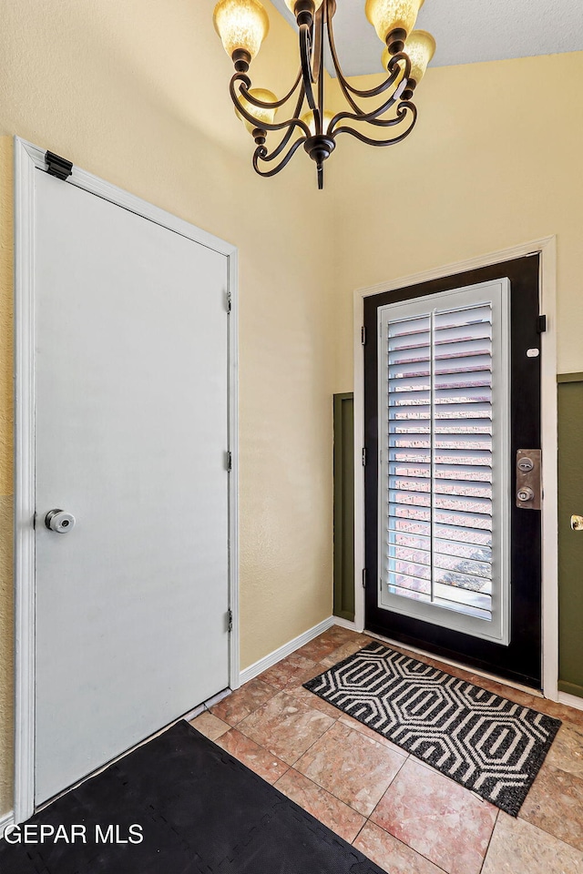 entrance foyer featuring tile patterned flooring, baseboards, and a chandelier