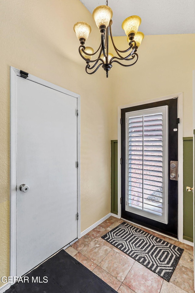 foyer featuring a notable chandelier and baseboards