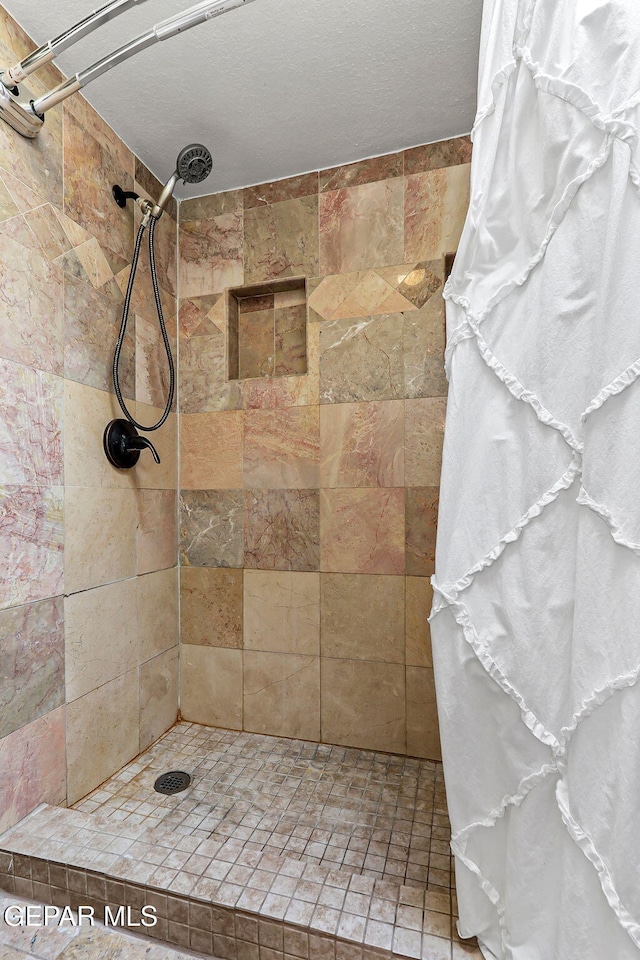 bathroom with a tile shower and a textured ceiling