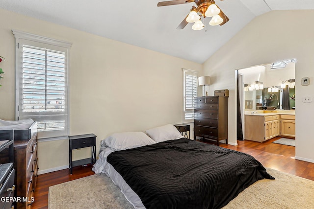 bedroom featuring baseboards, lofted ceiling, ensuite bathroom, a ceiling fan, and dark wood-style flooring