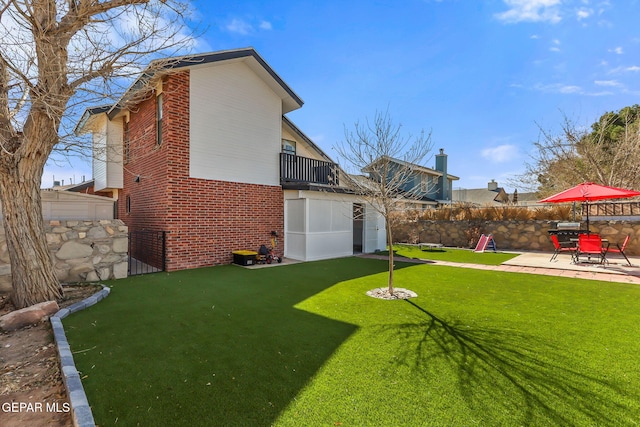 back of house with brick siding, a lawn, a patio, and a fenced backyard