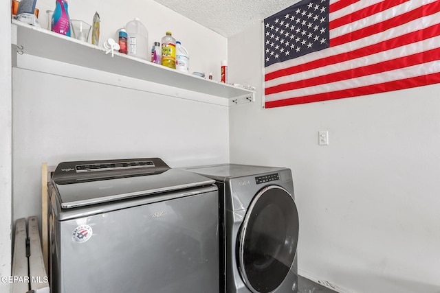 clothes washing area featuring laundry area, separate washer and dryer, and a textured ceiling