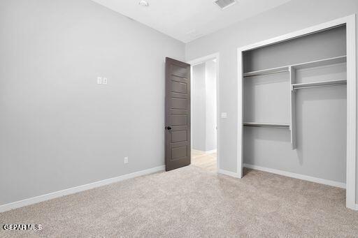 unfurnished bedroom featuring a closet, carpet flooring, visible vents, and baseboards