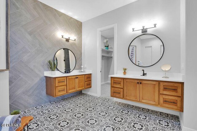 full bath featuring a sink, tile walls, two vanities, and tile patterned floors