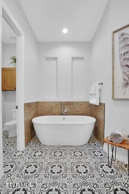 full bathroom with a freestanding tub, tile walls, a wainscoted wall, and tile patterned flooring