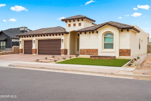 mediterranean / spanish home with stucco siding, concrete driveway, a garage, stone siding, and a tile roof