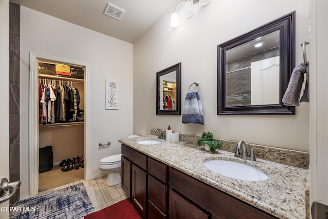 bathroom featuring a walk in closet, double vanity, visible vents, and a sink