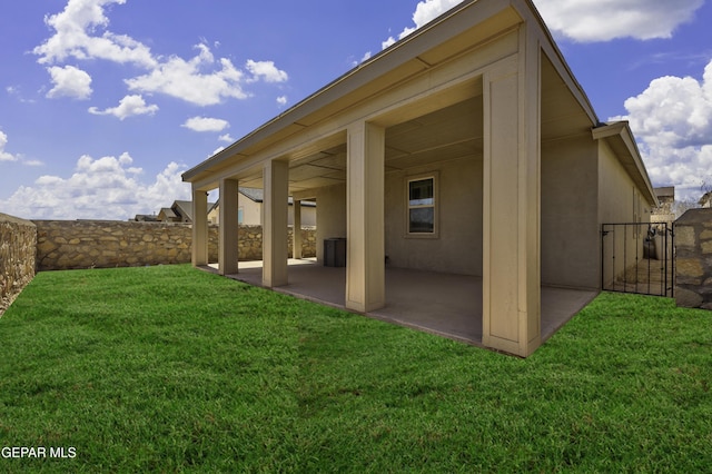 back of house with stucco siding, a lawn, a patio, and fence