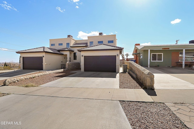 view of front of property featuring a garage, a tile roof, driveway, and stucco siding