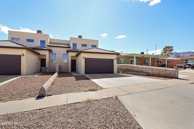 view of front of house with driveway, an attached garage, a tile roof, and stucco siding