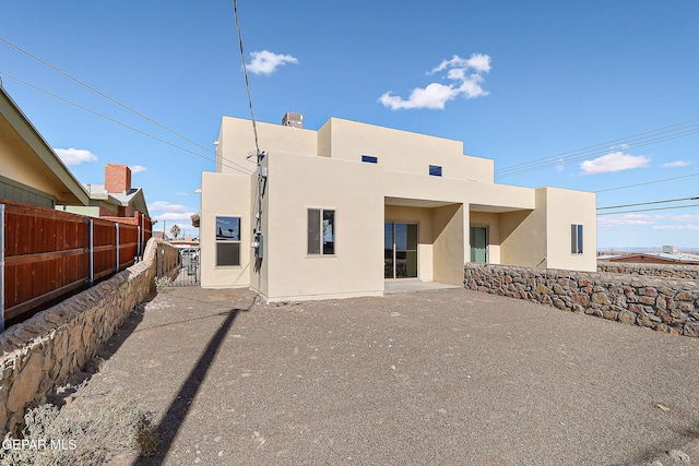 rear view of house featuring a patio, fence, and stucco siding