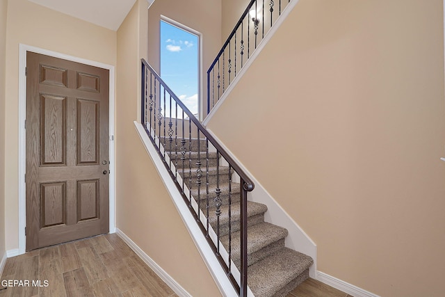 entryway featuring a towering ceiling, baseboards, and wood finished floors