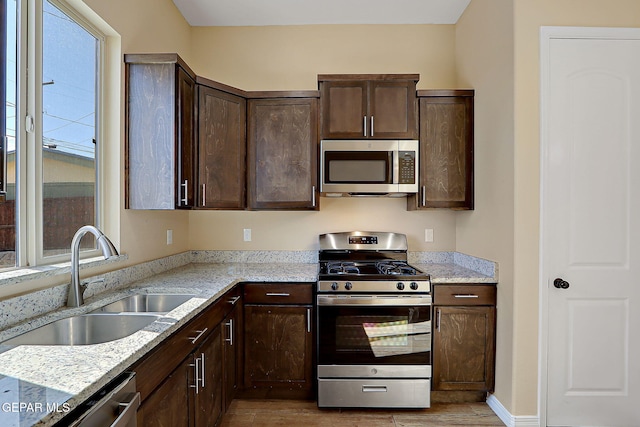 kitchen with a healthy amount of sunlight, dark brown cabinetry, appliances with stainless steel finishes, and a sink