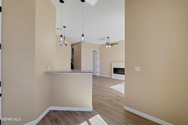 kitchen with light wood-type flooring, a glass covered fireplace, and baseboards