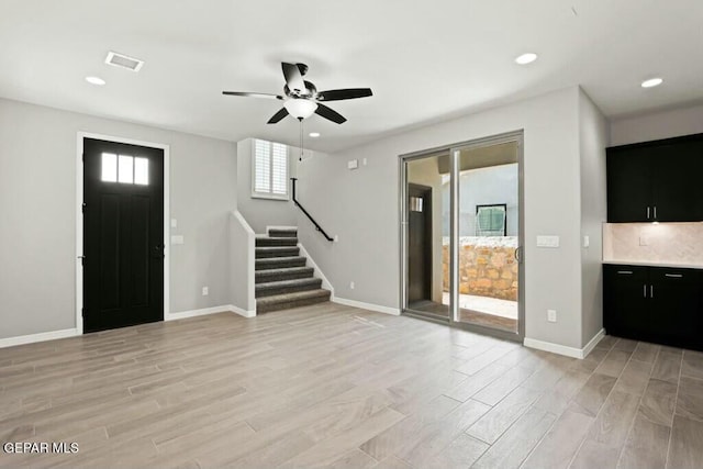 foyer with stairway, a ceiling fan, baseboards, and light wood-style flooring