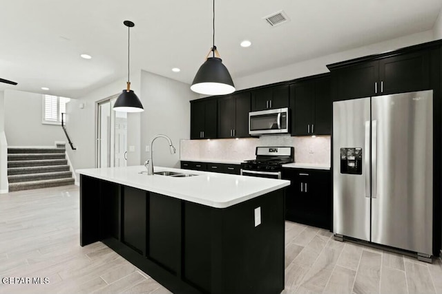 kitchen with a sink, visible vents, appliances with stainless steel finishes, and dark cabinetry