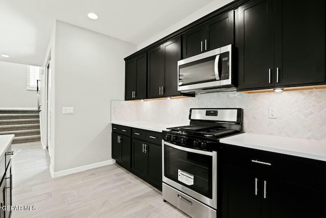 kitchen featuring backsplash, appliances with stainless steel finishes, light countertops, and dark cabinetry