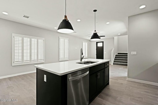 kitchen with a sink, stainless steel dishwasher, dark cabinets, and light countertops