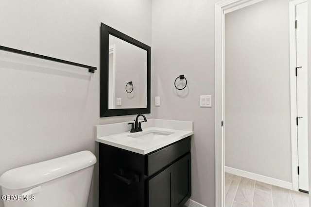 bathroom featuring baseboards, toilet, and vanity