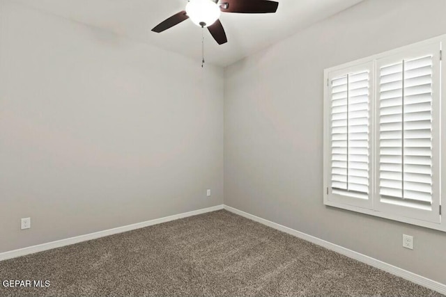 carpeted spare room featuring baseboards and a ceiling fan