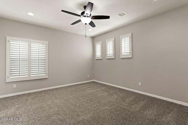 empty room with baseboards, visible vents, carpet floors, and ceiling fan