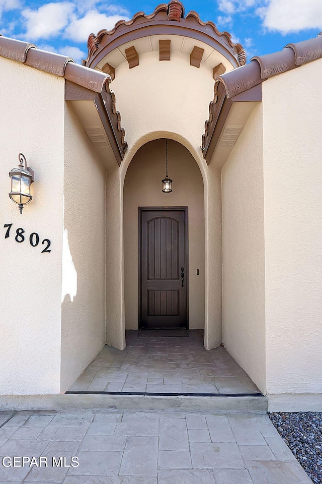 property entrance with a tile roof and stucco siding