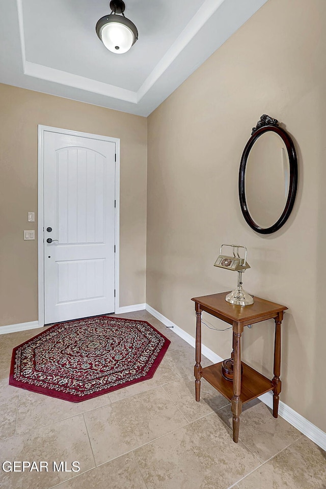 entryway with a tray ceiling and baseboards