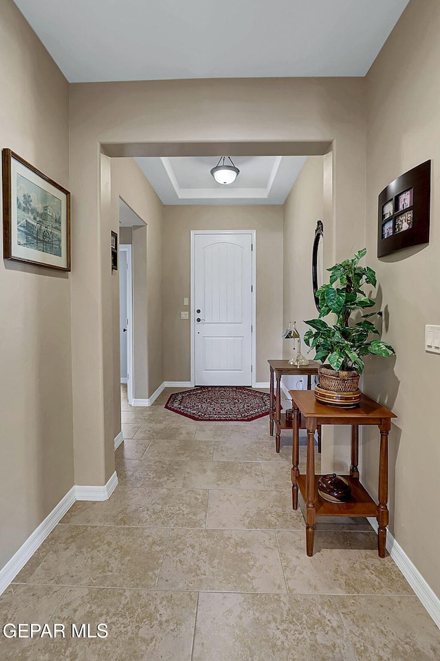 foyer with a raised ceiling and baseboards