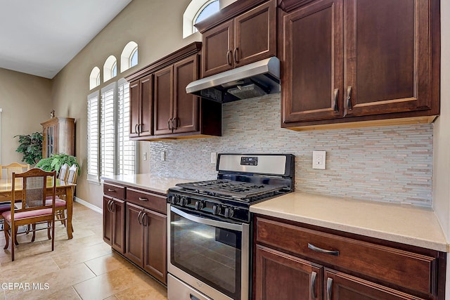 kitchen with stainless steel gas stove, under cabinet range hood, light countertops, and decorative backsplash