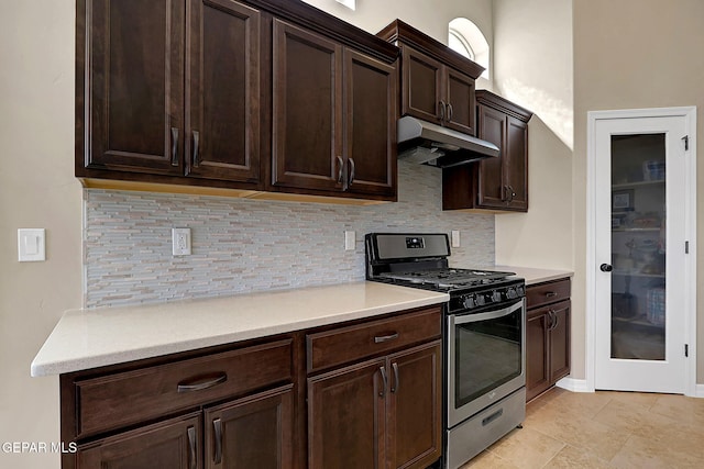 kitchen featuring tasteful backsplash, light countertops, stainless steel range with gas stovetop, dark brown cabinets, and under cabinet range hood