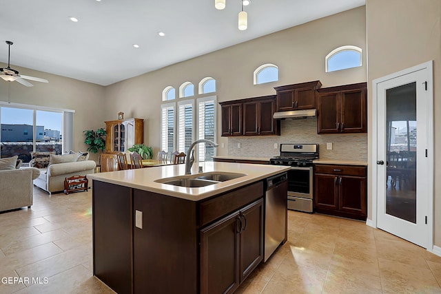 kitchen with light countertops, backsplash, appliances with stainless steel finishes, a sink, and under cabinet range hood