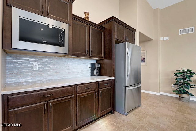 kitchen featuring dark brown cabinetry, tasteful backsplash, visible vents, stainless steel appliances, and light countertops