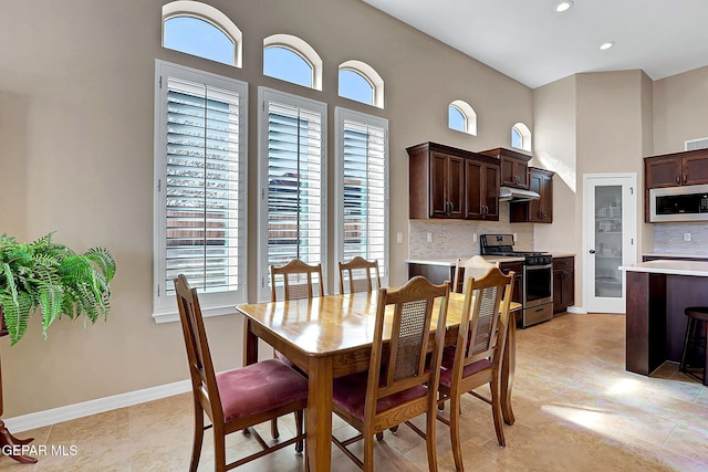 dining room featuring a towering ceiling, baseboards, and recessed lighting