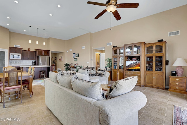 living area with a towering ceiling, ceiling fan, visible vents, and recessed lighting