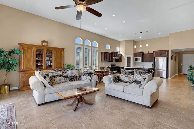 living area with a high ceiling, baseboards, a ceiling fan, and recessed lighting