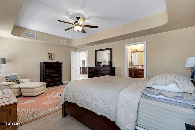 bedroom featuring ensuite bathroom, visible vents, a raised ceiling, and tile patterned floors