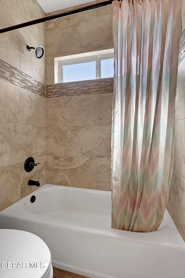 bathroom featuring shower / tub combo and toilet