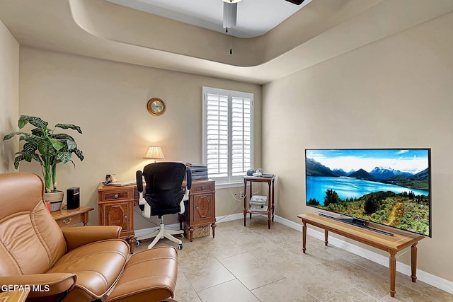 home office with a ceiling fan, a raised ceiling, and baseboards