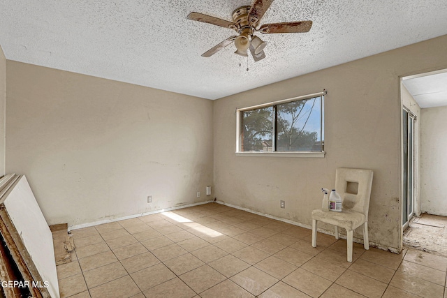 spare room featuring ceiling fan, a textured ceiling, and light tile patterned floors