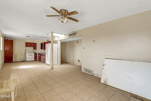 unfurnished living room featuring a textured ceiling, light tile patterned flooring, visible vents, and a ceiling fan