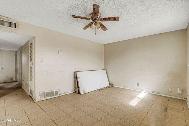 spare room featuring a ceiling fan, visible vents, a textured ceiling, and light tile patterned flooring