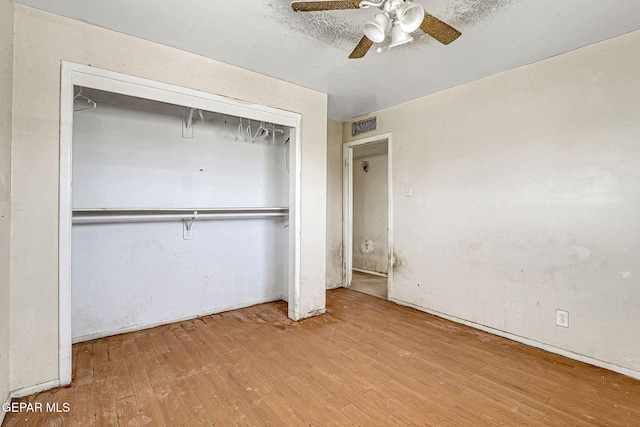 unfurnished bedroom with ceiling fan, a closet, wood finished floors, and visible vents