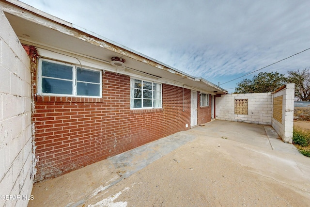 view of home's exterior with brick siding, a patio area, and fence