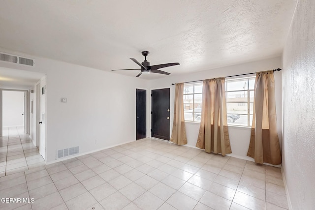 unfurnished room with a textured ceiling, ceiling fan, light tile patterned floors, and visible vents