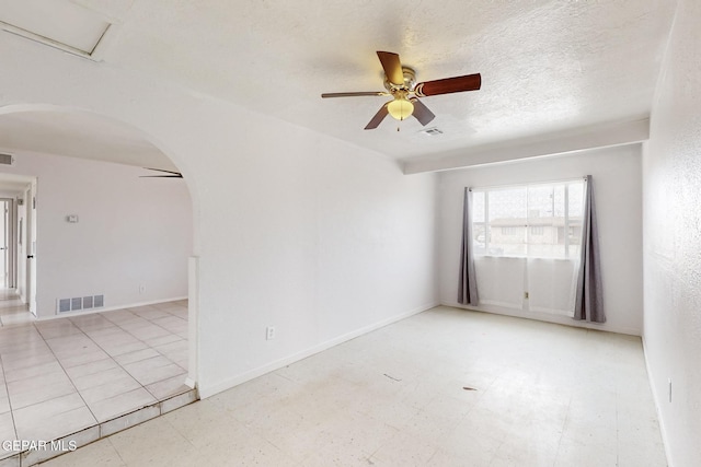 spare room with arched walkways, ceiling fan, a textured ceiling, and visible vents