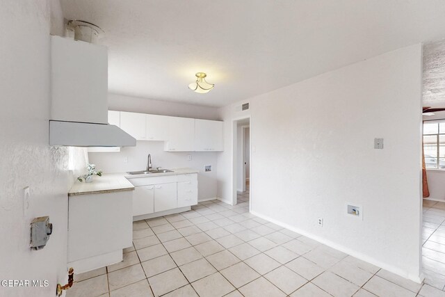 kitchen featuring light countertops, visible vents, white cabinets, a sink, and baseboards