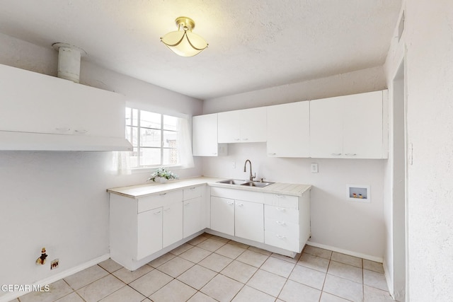 kitchen featuring light tile patterned floors, light countertops, a sink, and white cabinetry