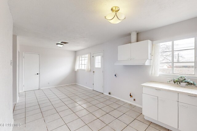 interior space with hookup for a gas dryer, visible vents, cabinet space, light tile patterned flooring, and electric dryer hookup