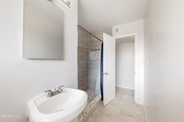 bathroom featuring a sink, visible vents, baseboards, tile patterned floors, and a stall shower